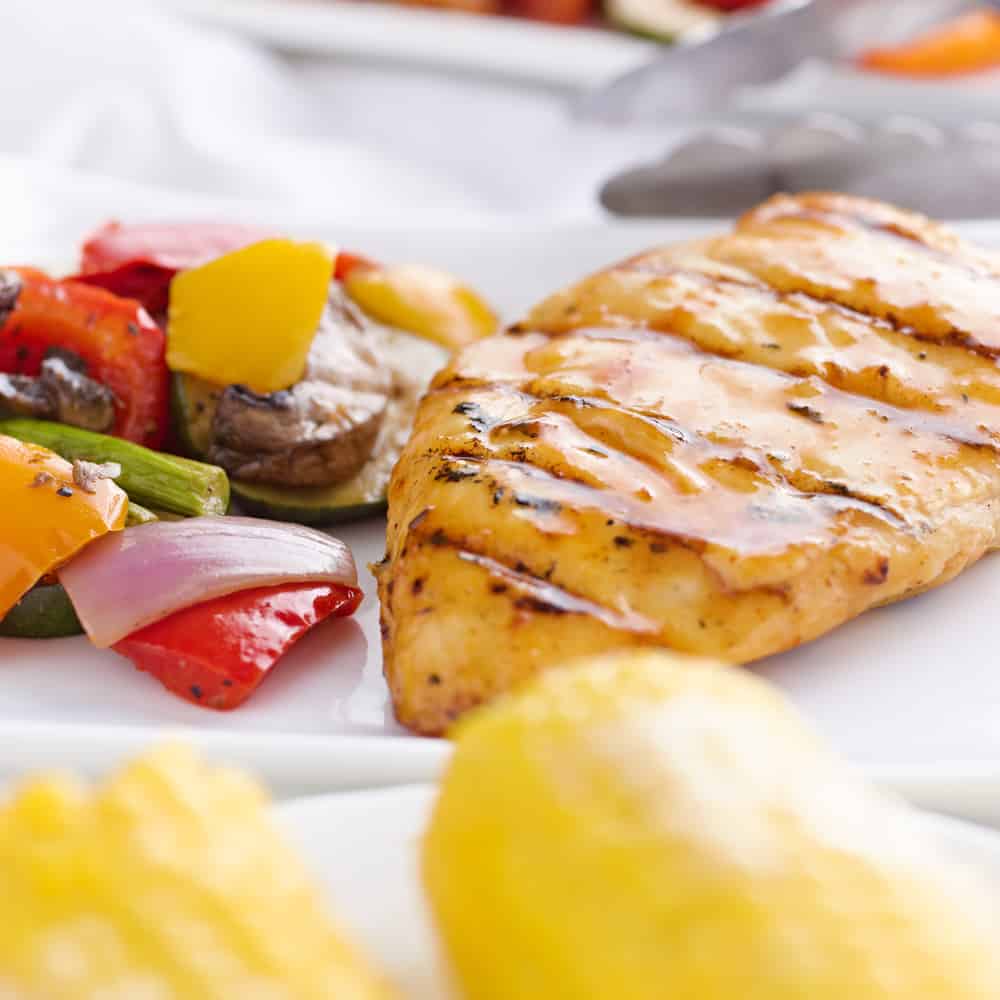 grilled barbecue chicken with vegetables and corn on the cob shot close up