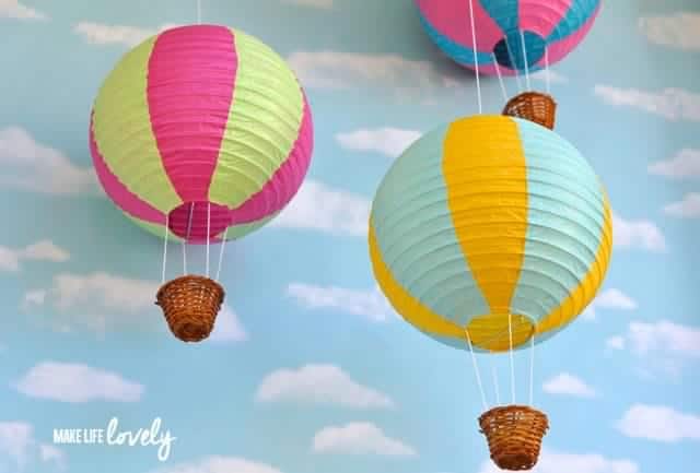 paper hot air balloons against a wall painted blue with clouds