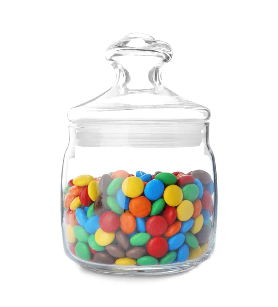 Jar with colorful candies on white background