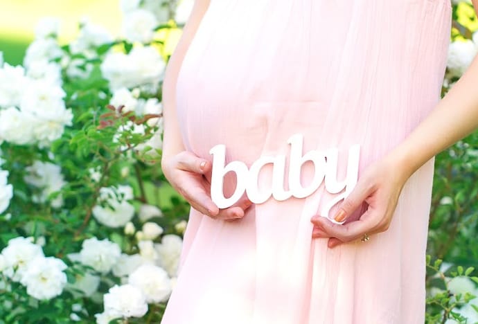 wooden word baby in front of pregnant woman
