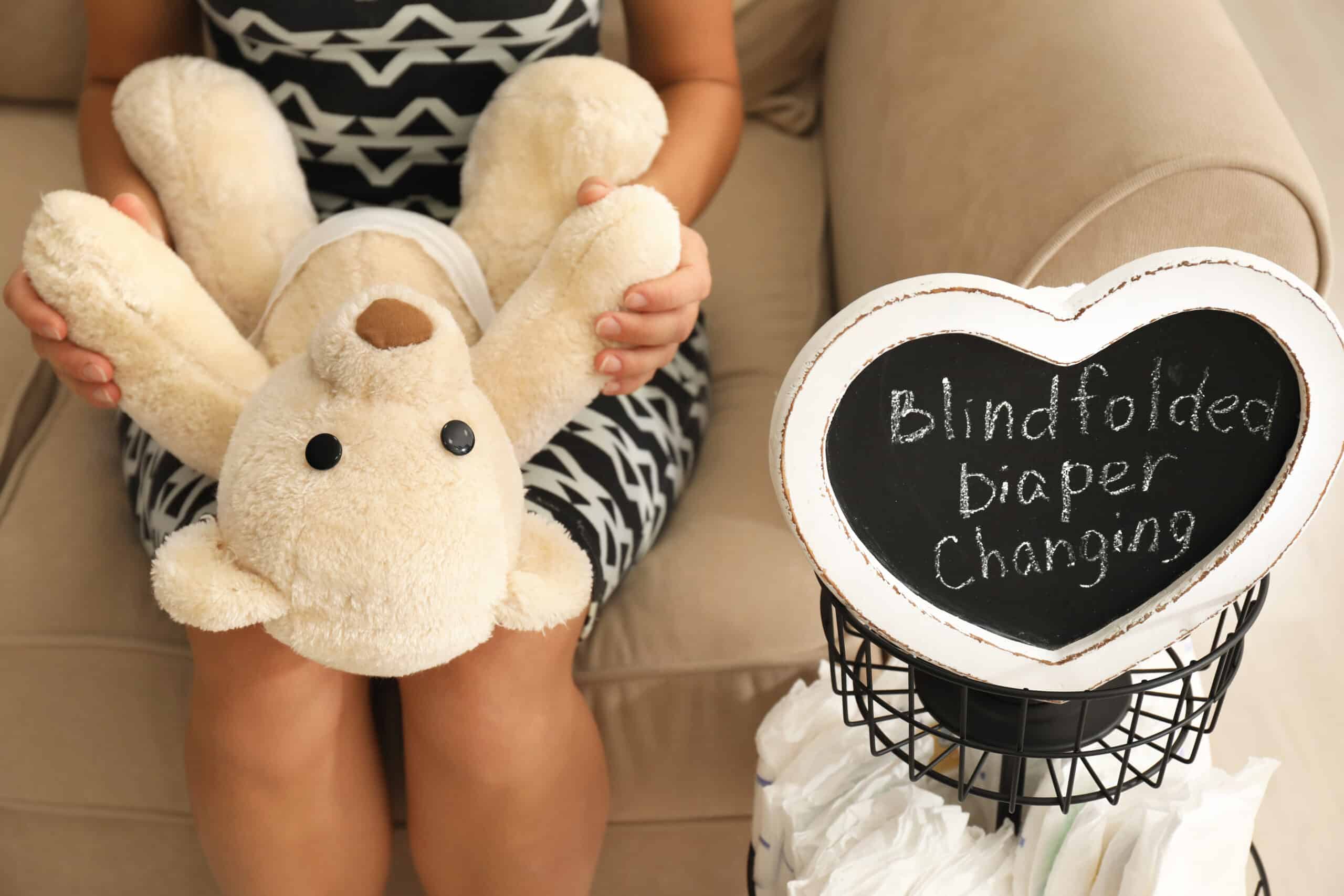 Woman putting diaper on toy during baby shower game