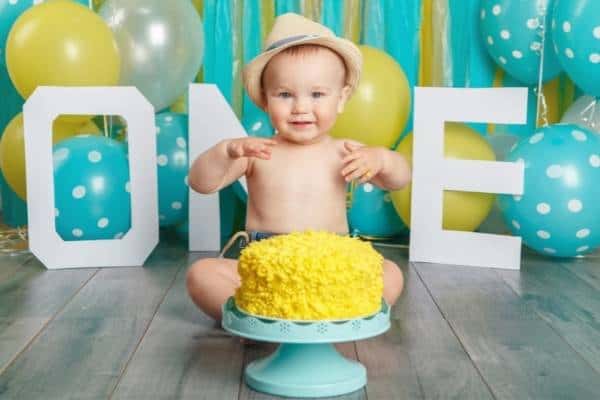 baby with yellow birthday cake