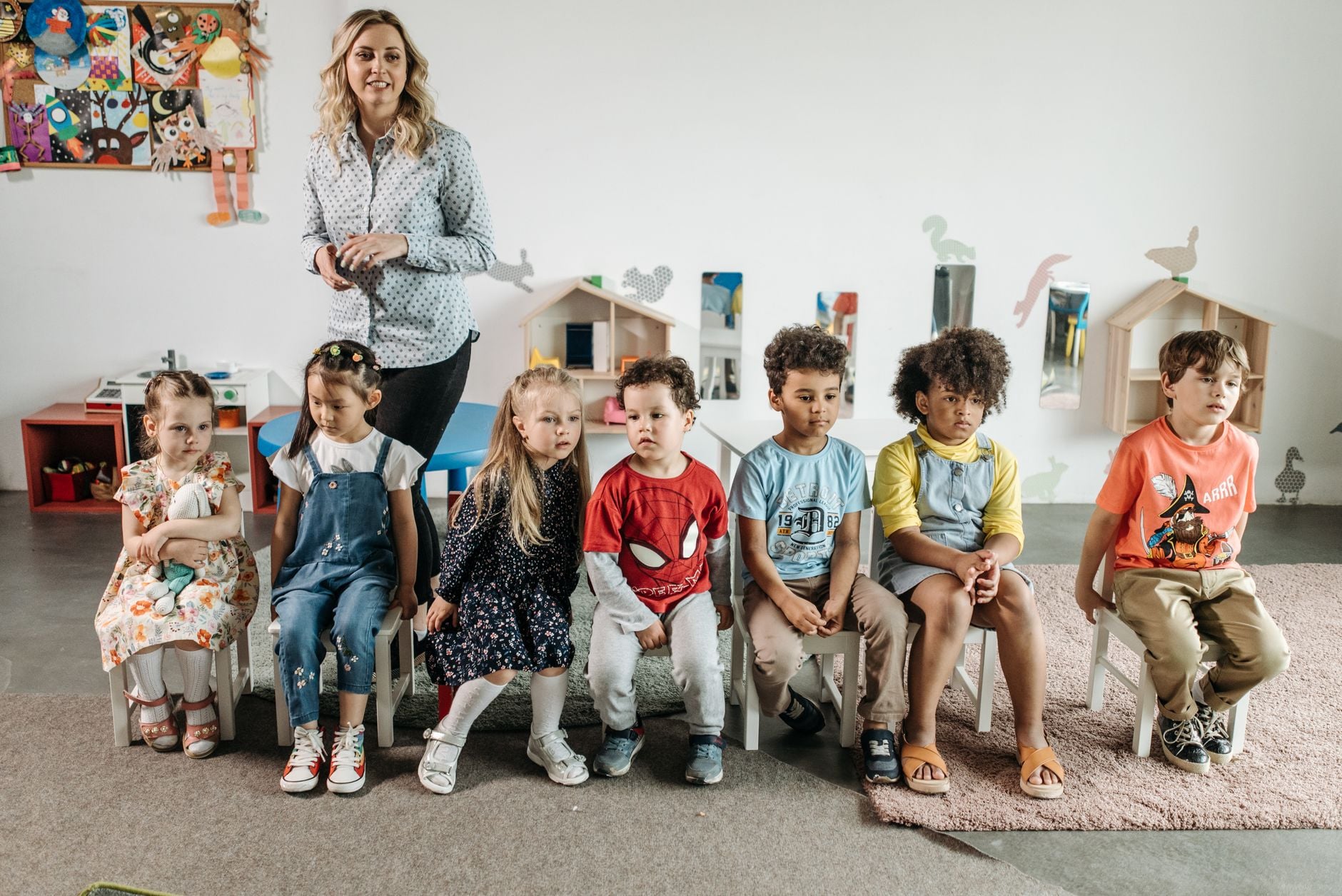 Children and teacher in a bright, diverse kindergarten classroom, enjoying games and learning.