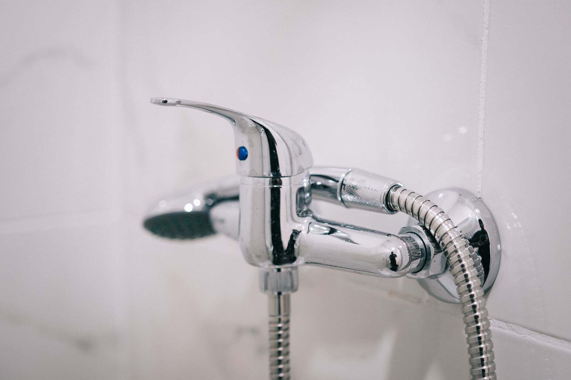 A detailed view of a sleek chrome shower faucet in a clean bathroom setting.