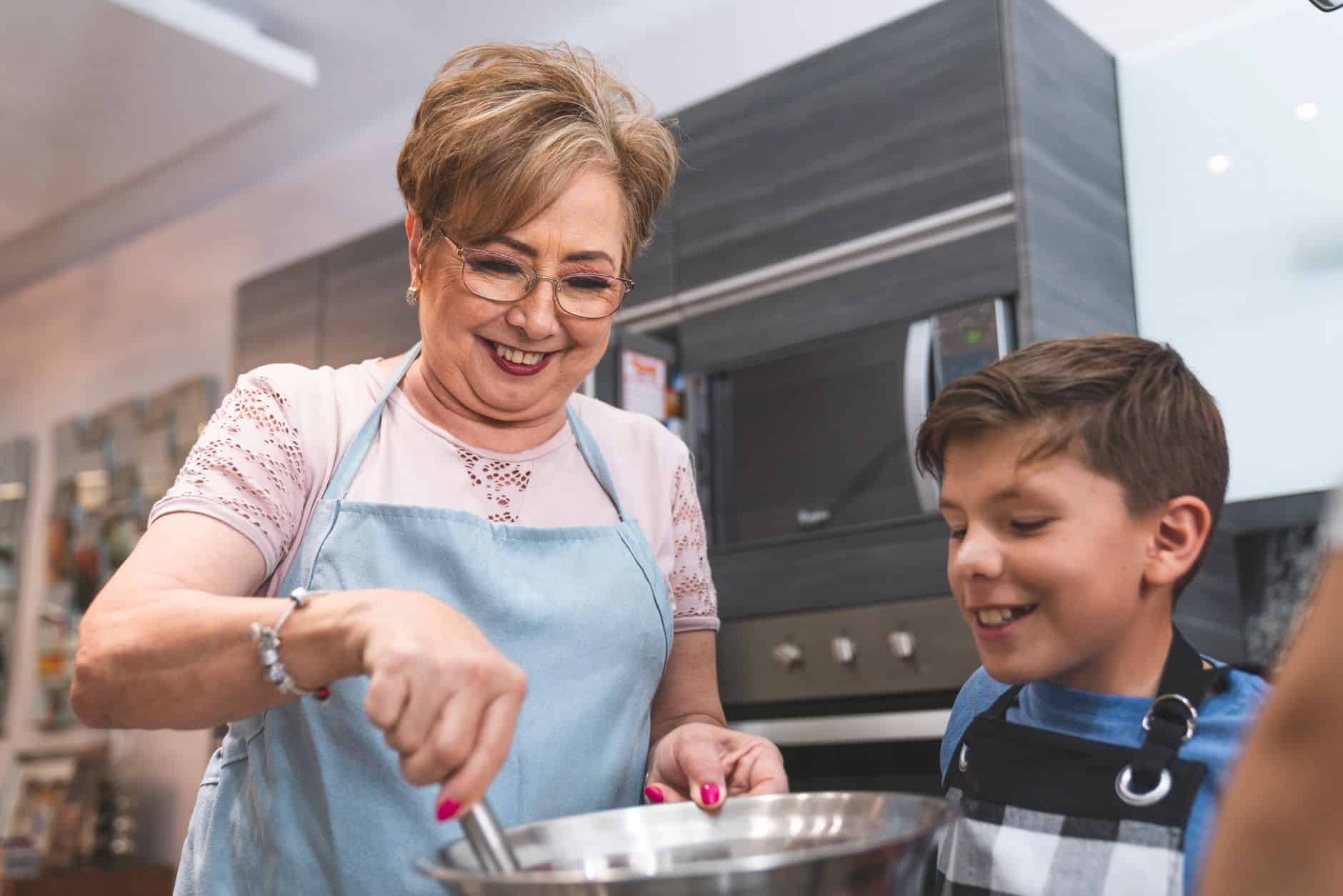 Senior woman and young boy enjoying cooking together in a modern kitchen setting.