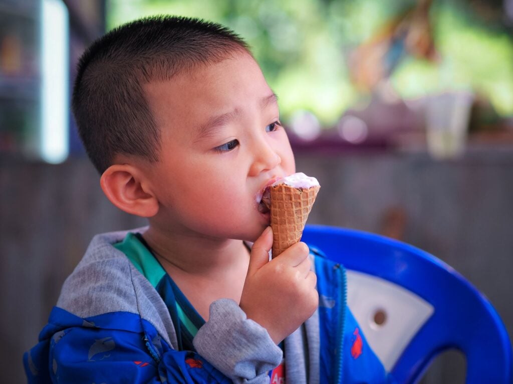 Cute young boy enjoying a delicious ice cream cone on a sunny day.