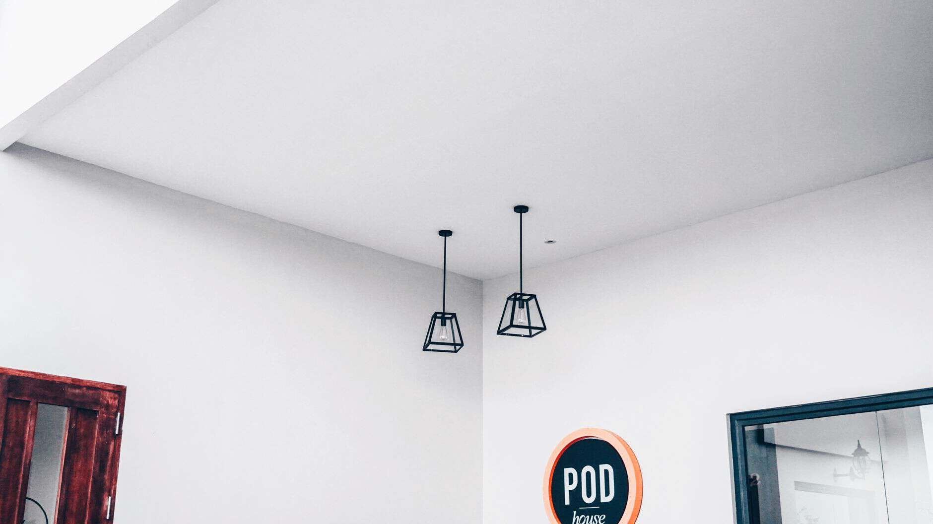 Modern minimalist interior featuring geometric pendant lights and a POD sign.